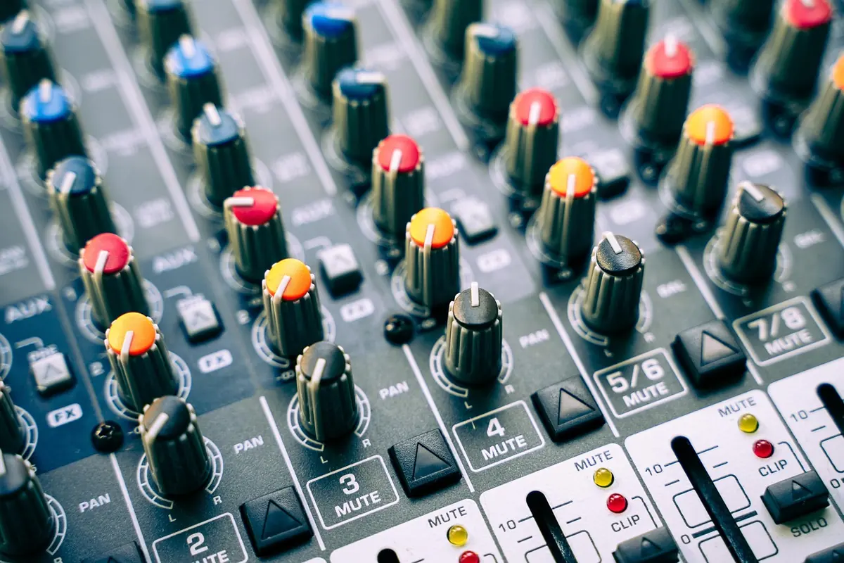 Close-up of an audio mixing console with rows of colored gain knobs and channel mute buttons